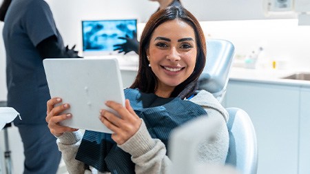 Woman smiling while holding handheld mirror