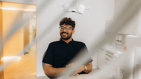 Patient with black glasses smiling in treatment chair