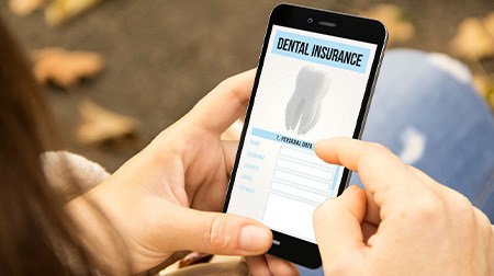 Hands zooming in on dental insurance on smartphone