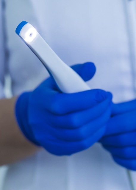Gloved hands holding a thin white intraoral camera