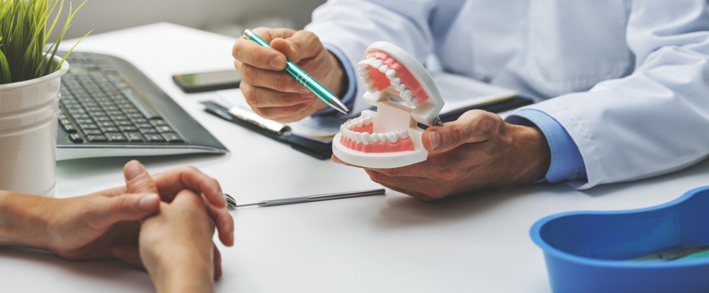 Dentist showing a model of a denture to a patient