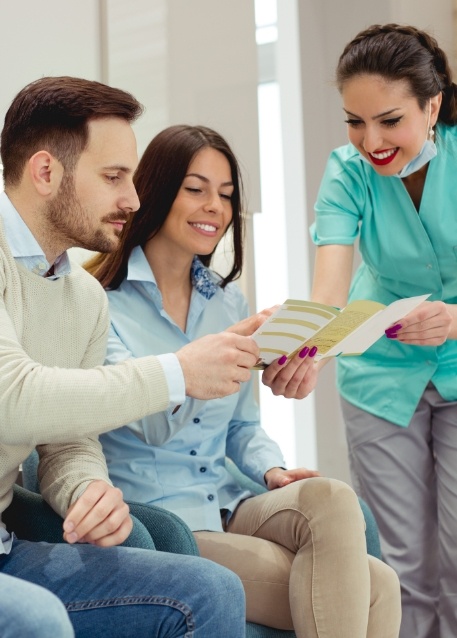 Dental team member showing a pamphlet to two patients