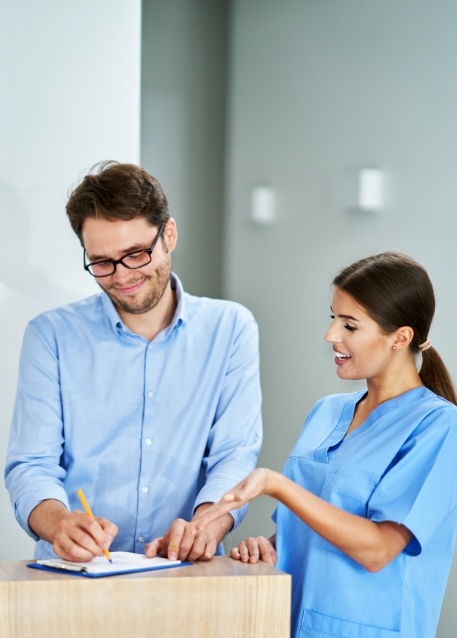Dental team member showing a patient where to sign on a clipboard