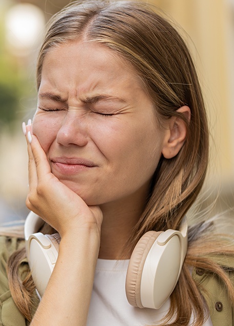 Woman experiencing toothache while walking outside