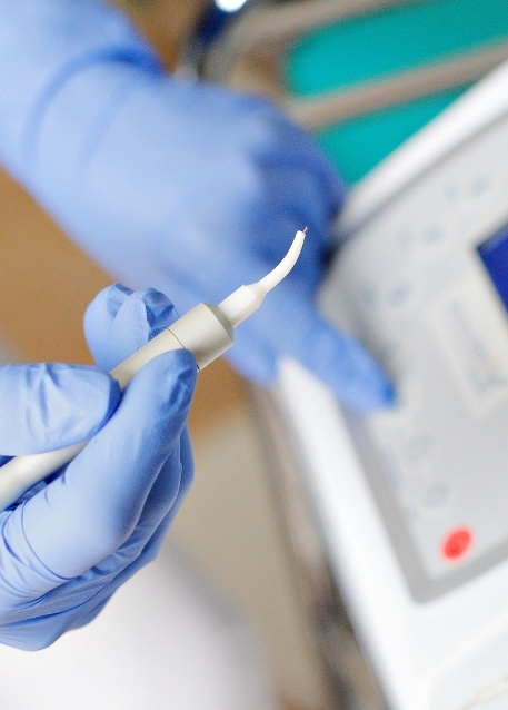 Gloved hand holding a pen like soft tissue dental laser