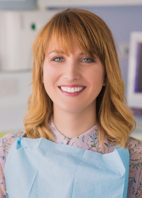 Woman with orange hair smiling in dental chair