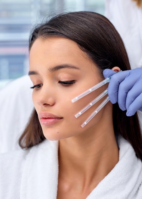Dentist holding needles near the face of a patient