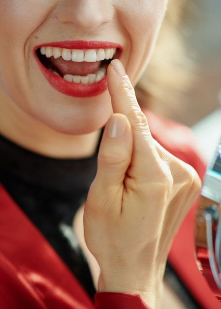Woman with red lipstick looking at her smile in mirror