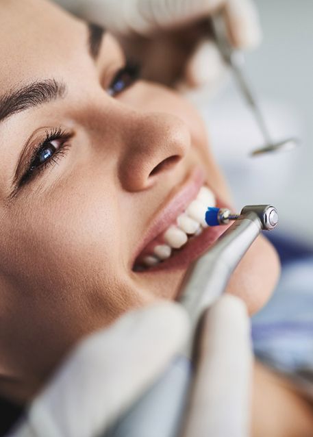 Closeup of woman smiling as dentist polishes her teeth