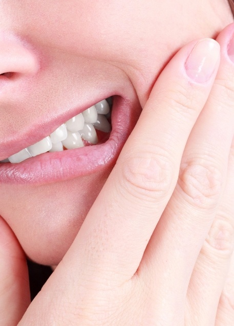 Person holding their jaw in pain before wisdom teeth removal in Tampa
