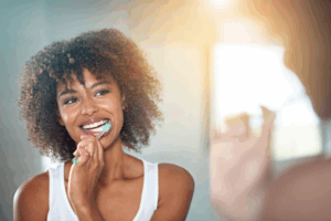 Woman brushing her teeth in front of her mirror